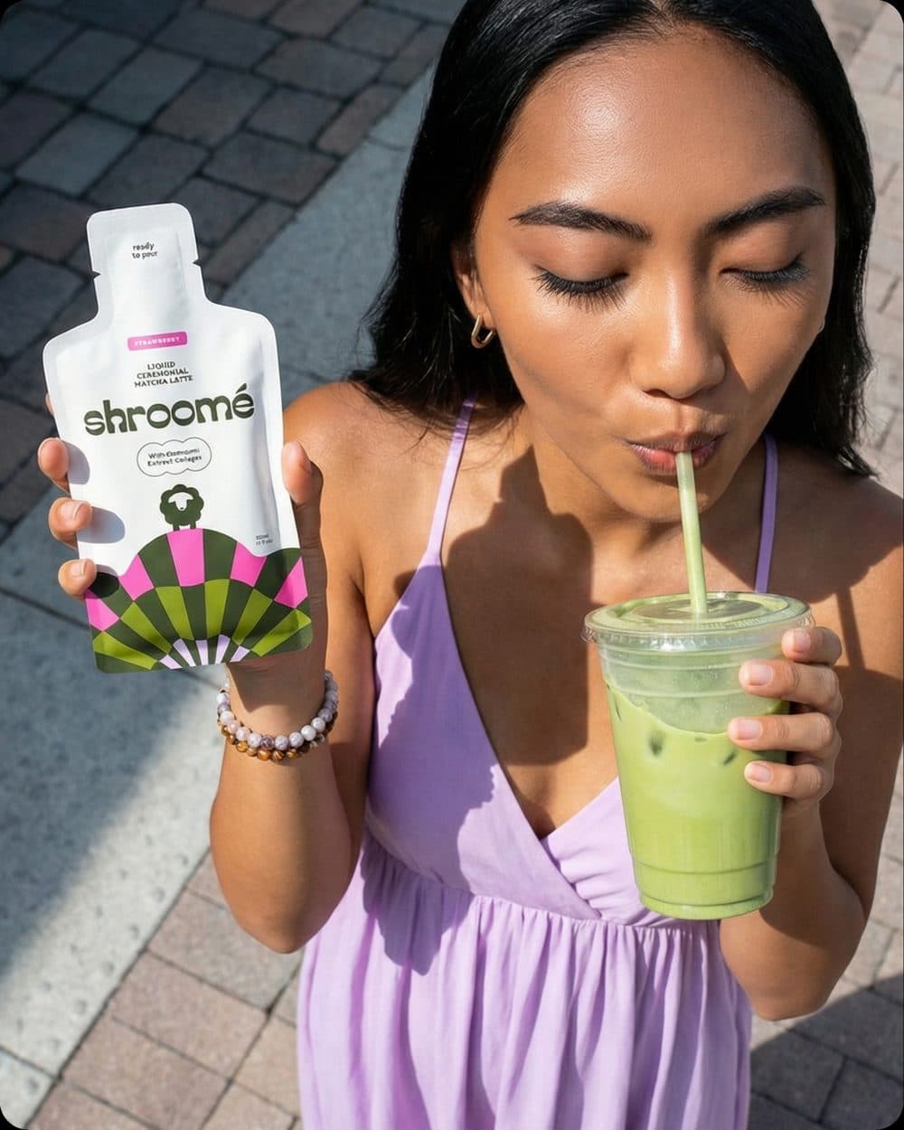 Sipping an iced shroomé matcha at home, strawberry sachet in hand